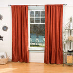 Rust velvet rod pocket curtains hung at a window