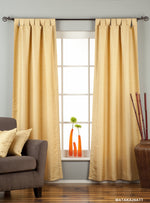 Golden raw silk tab top curtains hung at a window