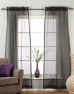 Black sheer tissue rod pocket curtains hung at a window