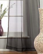Black sheer tissue tab top curtains hung at a window