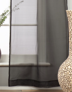 Black sheer tissue rod pocket curtains hung at a window