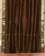 Brown sari grommet top curtains hung at a window