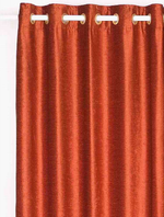 Rust velvet grommet top curtains hung at a window