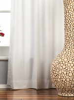 White velvet grommet top curtains hung at a window