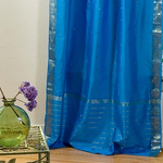 Blue sari tie top curtains hung at a window