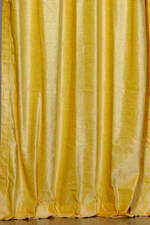 Yellow velvet tab top curtains hung at a window