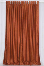 Rust velvet tab top curtains hung at a window