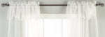 White sheer tissue rod pocket curtains hung at a window