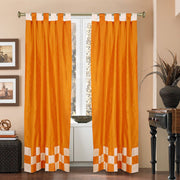 Orange sari tab top curtains hung at a window
