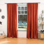 Rust velvet rod pocket curtains hung at a window
