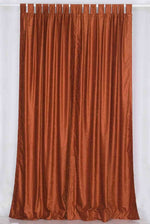 Rust velvet tab top curtains hung at a window