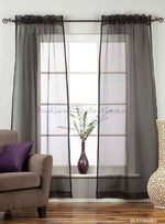 Black sheer tissue rod pocket curtains hung at a window