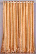 Peach velvet grommet top curtains hung at a window