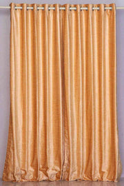 Peach velvet grommet top curtains hung at a window
