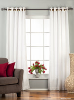White velvet grommet top curtains hung at a window