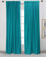 Turquoise velvet rod pocket curtains hung at a window