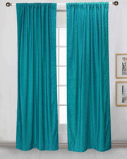 Turquoise velvet rod pocket curtains hung at a window