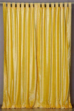 Yellow velvet tab top curtains hung at a window