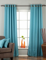 Turquoise raw silk ring top curtains hung at a window