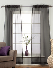 Black sheer tissue rod pocket curtains hung at a window