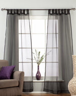 Black sheer tissue tab top curtains hung at a window