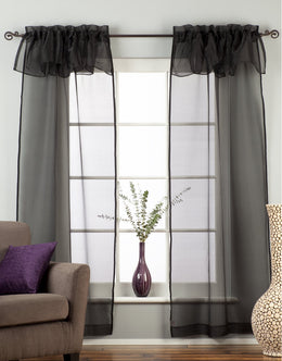 Black sheer tissue rod pocket curtains hung at a window