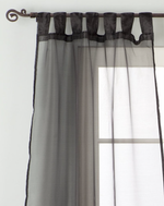 Black sheer tissue tab top curtains hung at a window