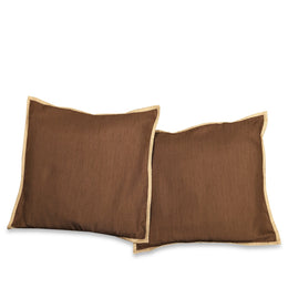 Brown with gold trim raw silk cushion covers arranged on a sofa