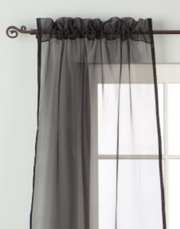 Black sheer tissue rod pocket curtains hung at a window