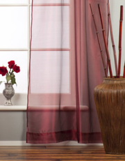 Maroon sheer tissue rod pocket curtains hung at a window