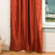 Rust velvet rod pocket curtains hung at a window
