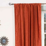 Rust velvet rod pocket curtains hung at a window