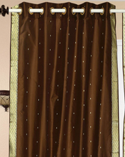 Brown sari grommet top curtains hung at a window