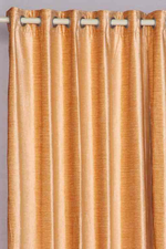 Peach velvet grommet top curtains hung at a window