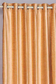 Peach velvet grommet top curtains hung at a window