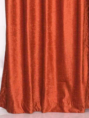 Rust velvet grommet top curtains hung at a window