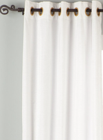 White velvet grommet top curtains hung at a window