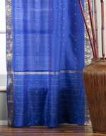Blue sari tie top curtains hung at a window