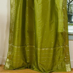 Olive green sari tie top curtains hung at a window