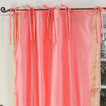 Pink sari tie top curtains hung at a window