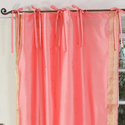 Pink sari tie top curtains hung at a window