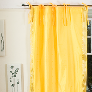Yellow sari tie top curtains hung at a window
