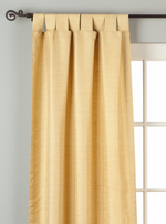 Golden raw silk tab top curtains hung at a window