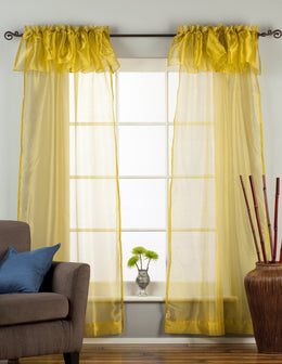 Gold sheer tissue rod pocket curtains hung at a window