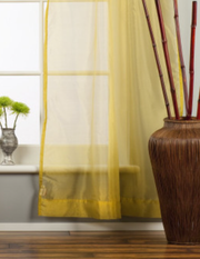 Gold sheer tissue rod pocket curtains hung at a window