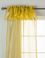 Gold sheer tissue rod pocket curtains hung at a window