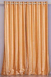 Peach velvet grommet top curtains hung at a window