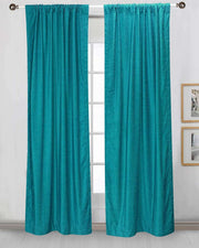 Turquoise velvet rod pocket curtains hung at a window